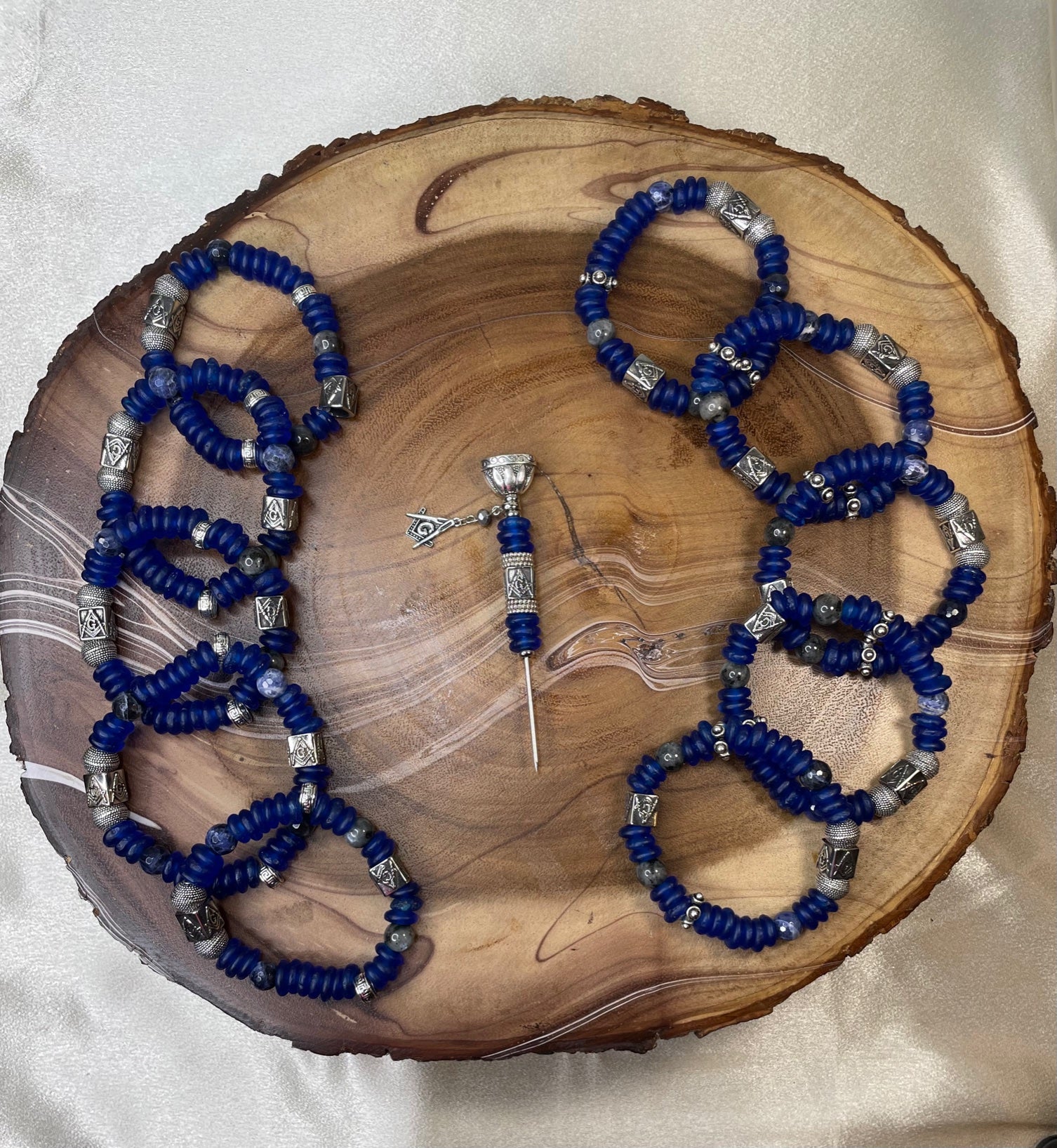 Assorted blue Masonic beaded bracelets with a matching cigar poker featuring a Masonic symbol.